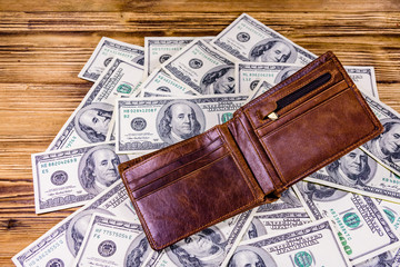 Opened brown leather wallet on the one hundred dollar banknotes
