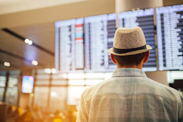 Solo traveler - man standing inside airport terminal looking at a schedule.  Travel and transportation themed image.