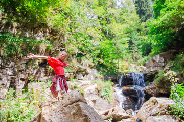 Naklejka premium Little girl enjoying view of waterfall in Krasnay Poliana