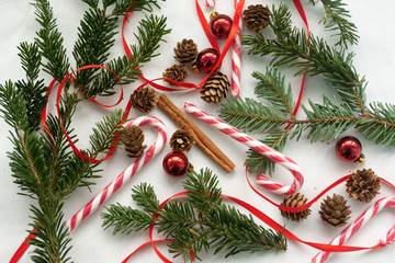 Christmas top view background with sugar cane, small cones, Christmas tree toys and red ribbon