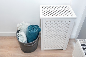 Laundry basket with towels. Interior of white stylish room with laundry basket