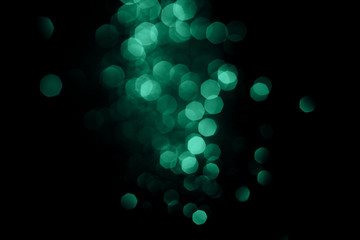 Dark abstract background with bright green bokeh.