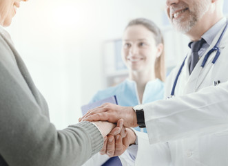 Obraz na płótnie Canvas Professional doctor holding a senior patient's hands