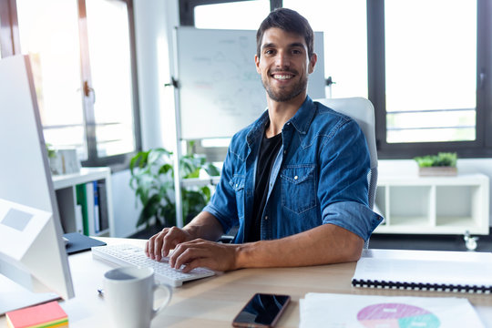 Software Developer Looking At Camera While Working With Computer In The Modern Startup Office.