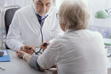 Obraz premium Doctor measuring blood pressure of a senior patient