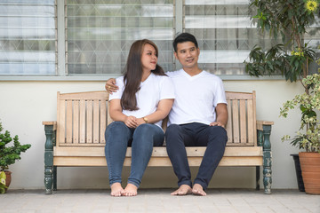Asian young couples wearing white T-shirts are relaxing and smiling at home.