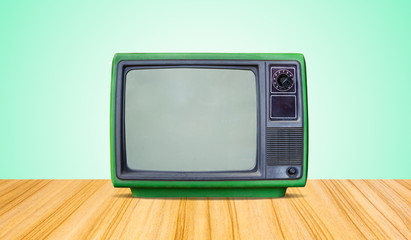 green retro old television receiver on table front gradient green wall background.