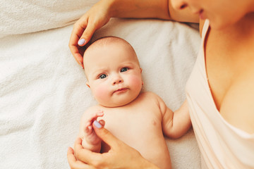 young beautiful mother lies with the baby on the bed, gently kisses, sleeping together