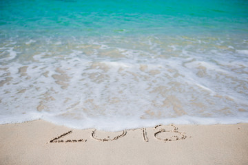 Happy New Year written in the white sand