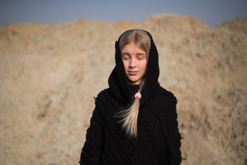 teen girl with blond hair in a hood in the desert