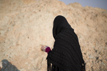 teen girl with blond hair in a hood in the desert