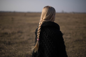 teen girl with blond hair in a hood in the desert