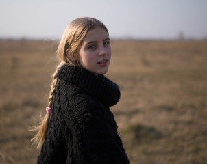 teen girl with blond hair in a hood in the desert