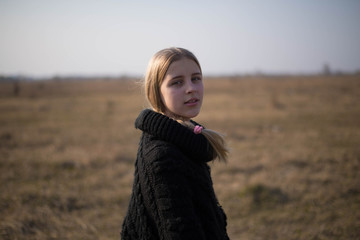 teen girl with blond hair in a hood in the desert