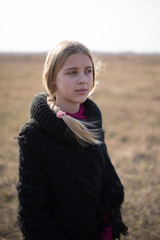 teen girl with blond hair in a hood in the desert