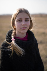 teen girl with blond hair in a hood in the desert