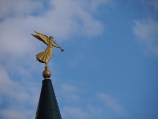 Fototapeta na wymiar Marmont holy saint angel Moroni on the spire with a trumpet deployed to the east. Religious symbol on a blue sky background closeup.