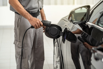 Closeup asian Technician hand is charging the electric car or EV in service center for maintainance, Eco-friendly alternative energy concept