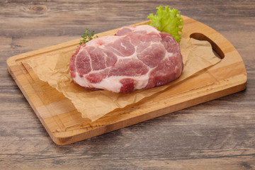 Raw pork steak over wooden board