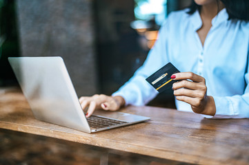 woman sat with a laptop and paid with a credit card in a coffee shop.