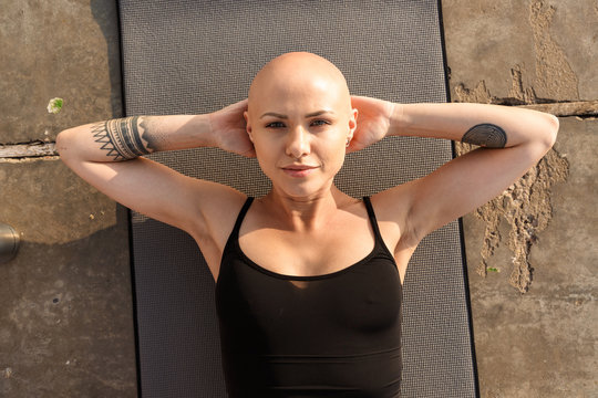 Image of satisfied bald woman lying on mat while working out