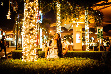An Indian girl admiring bright decorative lights in a market at night during festive season in...