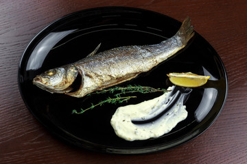 baked sea bass with sauce and lemon in a plate