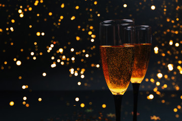Two glasses of champagne on a black background with New Year's lights. Christmas concept. background for your design.