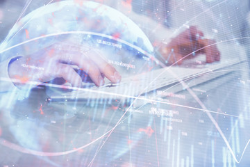 Double exposure of graph with man typing on computer in office on background. Concept of hard work. Closeup.