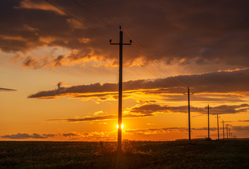 Obraz premium Power line on the background of beautiful dramatic sunset . Electrical wires on poles