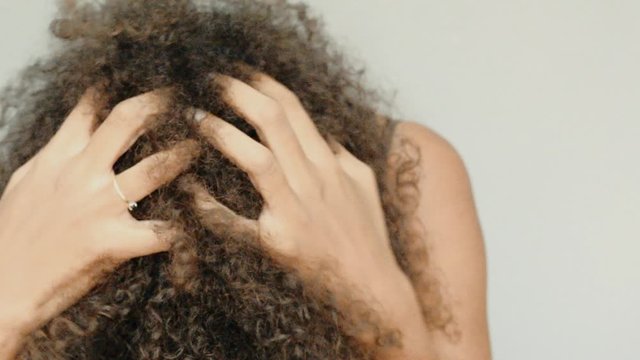 Slow motion of a black woman touvhing her afro hair. Closeup.