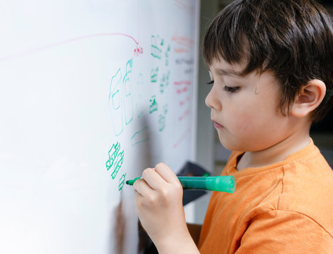 Portrait school kid drawing cartoon tank on white boad, Child boy holding colour pen write on board, Education concept