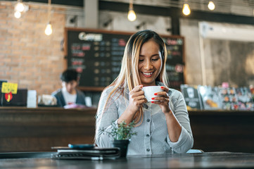 woman sitting happily drinking coffee in cafe shop