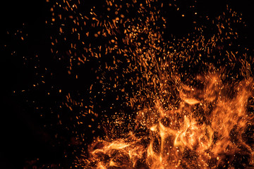 Burning sparks flying. Beautiful flames. Fiery orange glowing flying away particles on black...