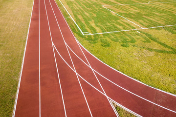 Top view of red running tracks and green grass lawn. Infrastructure for sports activities.