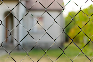 Country house in nature surrounded by a metal fence made of mesh for security against thieves and theft