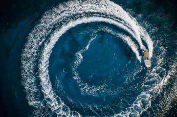 Speed boat in mediterranean sea making a cyrcle from bubbles, aerial view