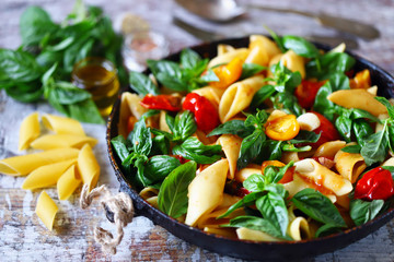 Appetizing pasta in a pan with tomatoes, basil and spices. One pan pasta. Italian vegan pasta. Selective focus. Macro.