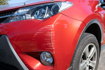 Fototapeta na wymiar Red vehicle bumper deeply scratched closeup