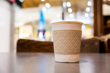 Disposable coffee cup on bright blurred background with copy space