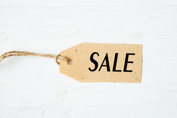 price tag label with word SALE on wooden background One paper blank tags with word SALE with rope on wooden background.