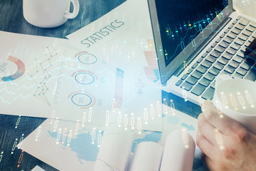 Double exposure of man's hands writing notes of stock market with forex graph background. Concept of research and trading.