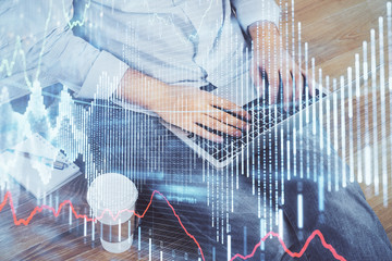 Double exposure of man's hands writing notes of stock market with forex graph background. Concept of research and trading.