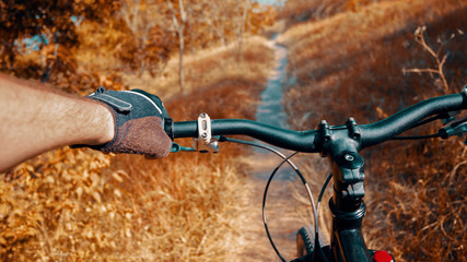 Mountain bike background. Bicyclist's hand and mtb handlebar