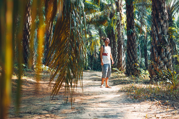 young man tourist on the road it tropical forest at sunset
