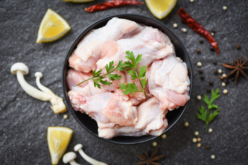 raw chicken wings with lemon chilli herbs and spices and mushroom on black plate top view - Raw uncooked chicken meat marinated with ingredients for cooking