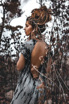 portrait of beautiful young woman through the dry branches outdoors