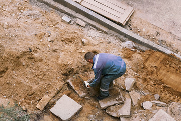 man worker carries a heavy stone with his hands. manual labor concept.