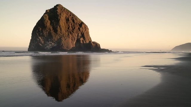 Haystack Rock Cannon Beach Dawn 4K UHD. Sunrise at Haystack Rock in Cannon Beach, Oregon as the surf washes up onto the beach. United States.