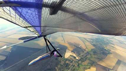 Two hang glider pilots soarabove terrain on high altitude.